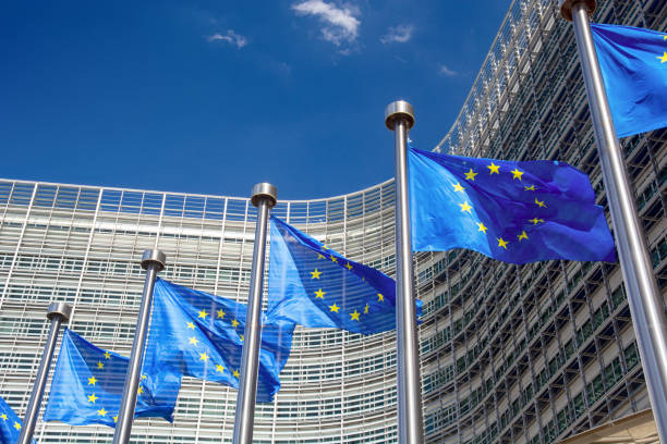 UK-EU Relations in 2026: TCA Review, SPS Deals and Trade Impact Union Jack and European Union flag flying side by side outside an official diplomatic summit building. UK-EU relations 2026