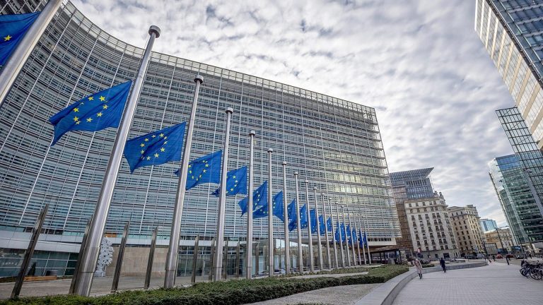 European Union flags outside the European Commission building in Brussels, illustrating EU AI Act business compliance.